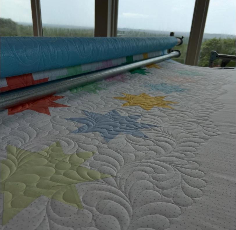 Colorful star blocks with custom feather quilting on the longarm frame