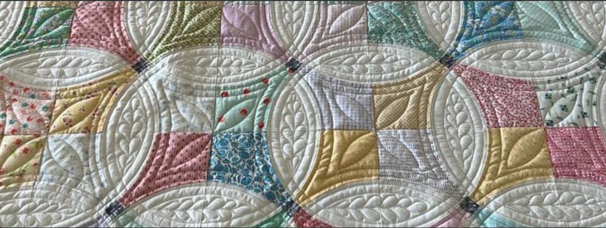 Soft pastel cathedral windows pattern with intricate feathered leaf quilting
